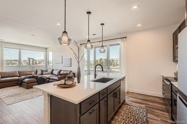 kitchen featuring light countertops, dark brown cabinets, dark wood-style floors, and a sink