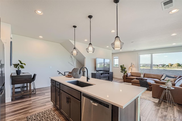 kitchen featuring stainless steel dishwasher, light countertops, light wood-style flooring, and a sink