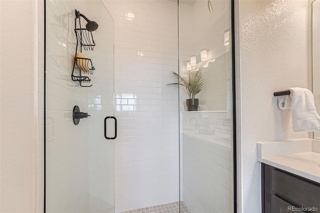 bathroom featuring a stall shower, vanity, and a textured wall