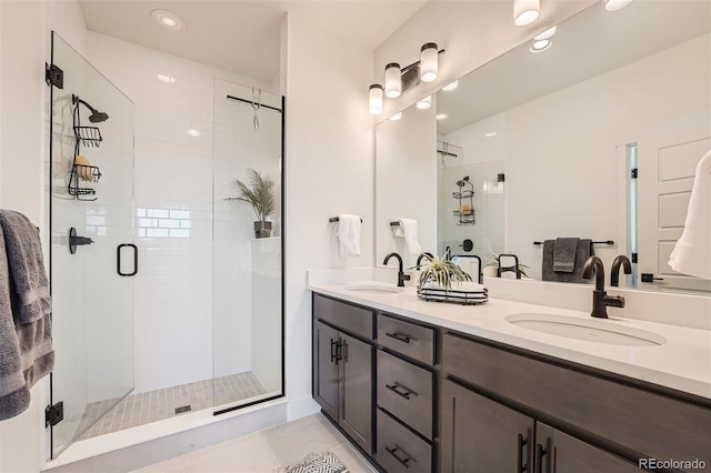 bathroom featuring double vanity, a stall shower, and a sink