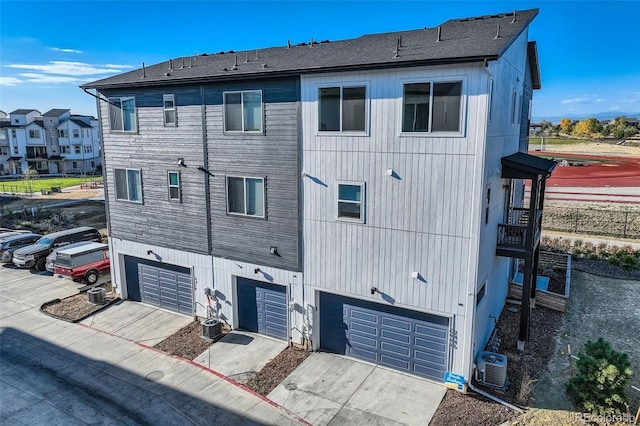 exterior space featuring an attached garage, driveway, and central AC