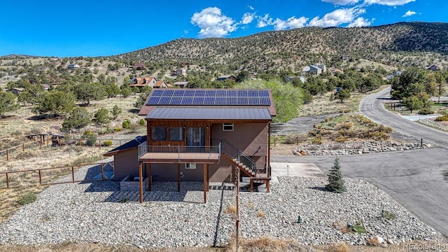 10145 Piute Dr, Salida, CO 81201 - view of front of property featuring stairs, roof mounted solar panels, metal roof, a deck with mountain view, and a patio area