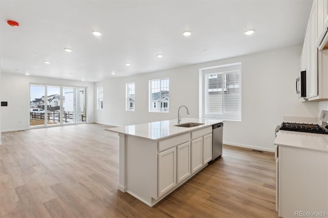 kitchen with white cabinetry, sink, stainless steel appliances, and an island with sink