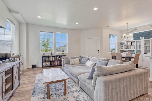 living area with light wood-style floors, a wealth of natural light, and an inviting chandelier