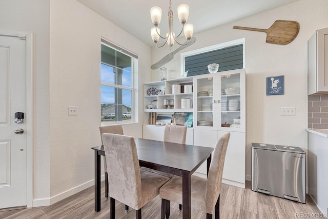 dining room with light wood-style floors, baseboards, and a notable chandelier