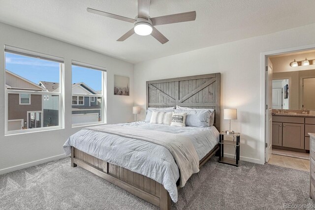 bedroom with light carpet, ceiling fan, ensuite bath, and baseboards