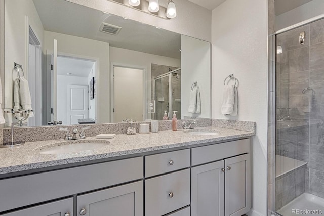 full bathroom with double vanity, a stall shower, visible vents, and a sink