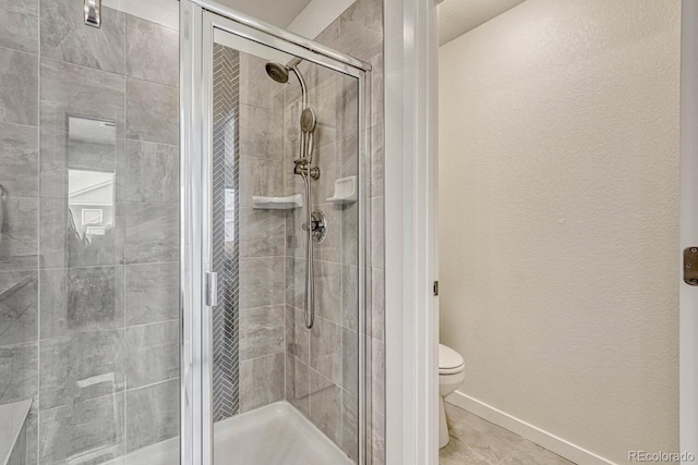 full bath featuring toilet, a shower stall, baseboards, and tile patterned floors