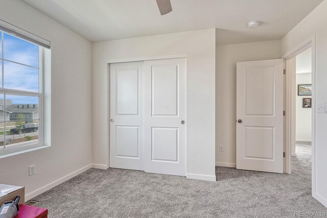 unfurnished bedroom featuring light carpet, ceiling fan, a closet, and baseboards