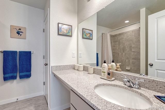 bathroom with curtained shower, tile patterned floors, baseboards, and vanity