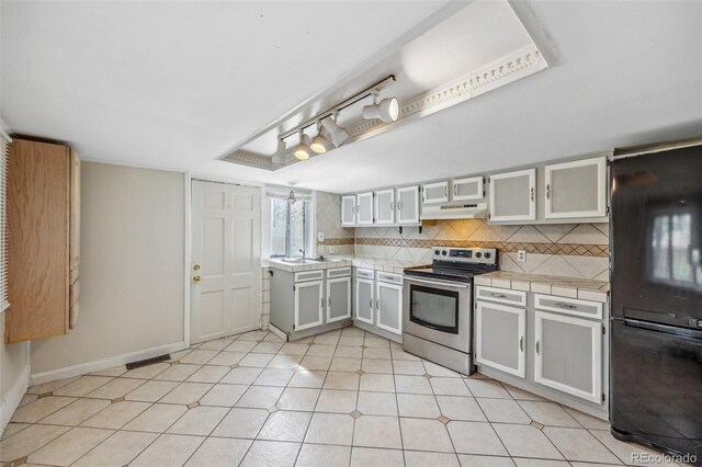 530 S Quitman St, Denver, CO 80219 - kitchen featuring electric stove, under cabinet range hood, tile countertops, decorative backsplash, and a sink