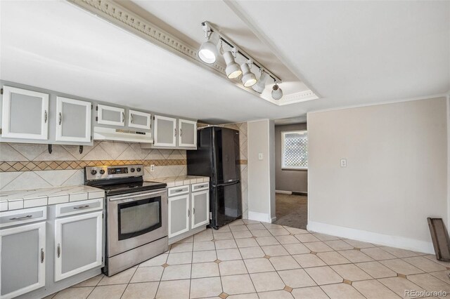 530 S Quitman St, Denver, CO 80219 - kitchen with stainless steel electric stove, freestanding refrigerator, under cabinet range hood, tile counters, and decorative backsplash
