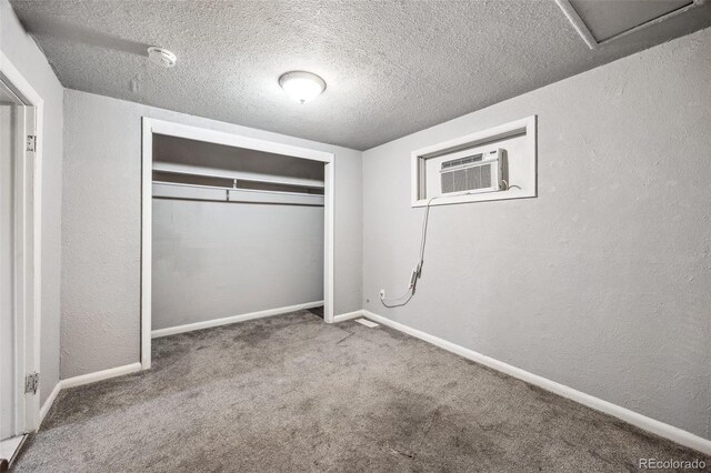 530 S Quitman St, Denver, CO 80219 - unfurnished bedroom with a textured wall, a closet, a textured ceiling, an AC wall unit, and carpet flooring