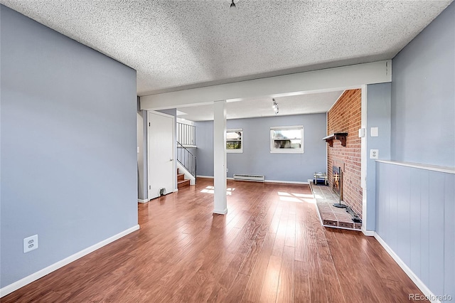 1796 S Yampa Way, Aurora, CO 80017 - unfurnished living room featuring a baseboard radiator, wood finished floors, stairs, a textured ceiling, and a brick fireplace