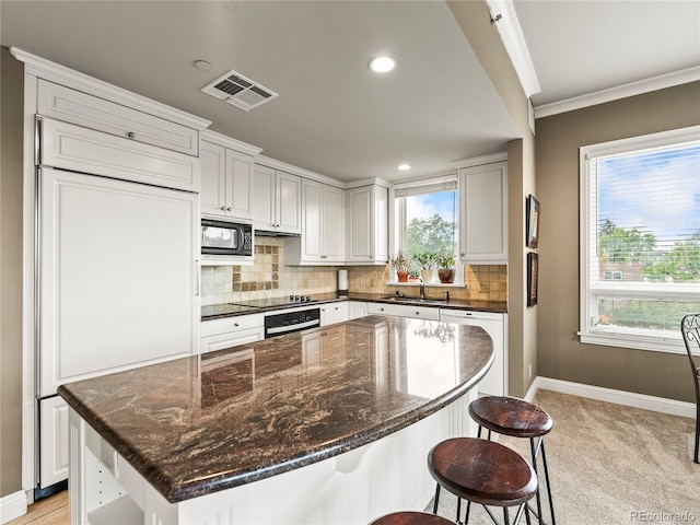 400 E 3rd Ave Unit 305, Denver, CO 80203 - kitchen featuring black appliances, baseboards, decorative backsplash, crown molding, and a breakfast bar area