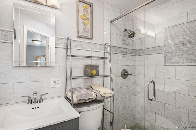 bathroom featuring vanity, toilet, a shower with door, and tile walls