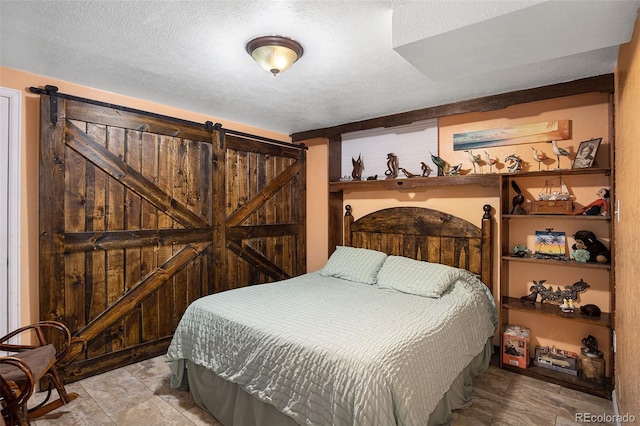 bedroom featuring a barn door and a textured ceiling