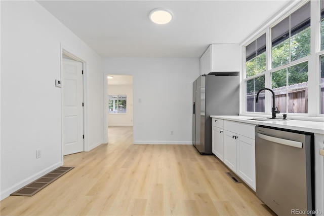 kitchen featuring stainless steel appliances, light hardwood / wood-style floors, and white cabinetry