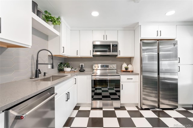 kitchen featuring stainless steel appliances, white cabinetry, a sink, and tile patterned floors