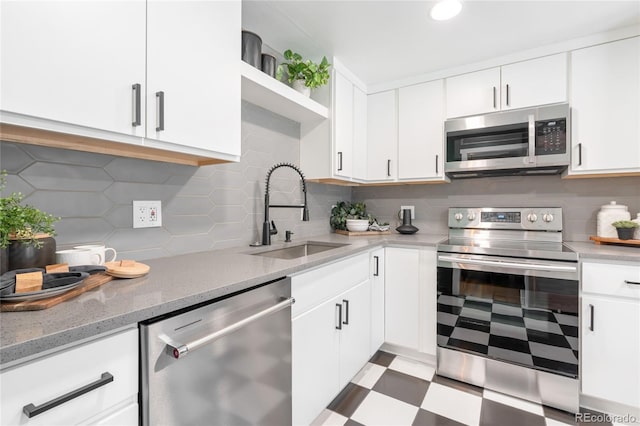 kitchen featuring backsplash, appliances with stainless steel finishes, white cabinets, and a sink