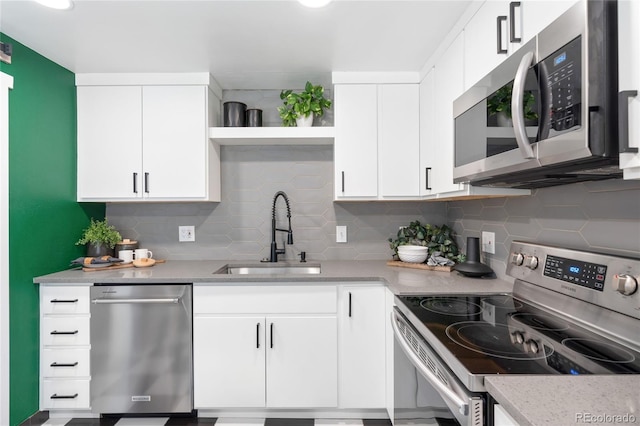 kitchen featuring open shelves, appliances with stainless steel finishes, a sink, and tasteful backsplash