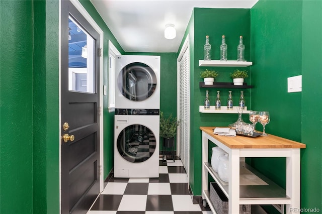 clothes washing area with laundry area, stacked washing maching and dryer, and tile patterned floors