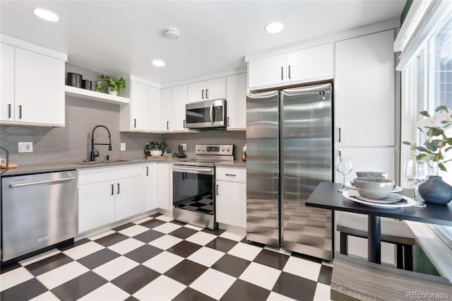 kitchen with light floors, open shelves, stainless steel appliances, decorative backsplash, and a sink