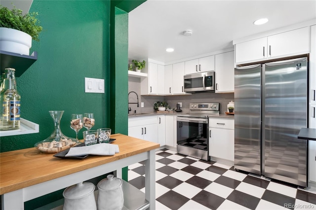 kitchen with white cabinetry, appliances with stainless steel finishes, a sink, and tile patterned floors