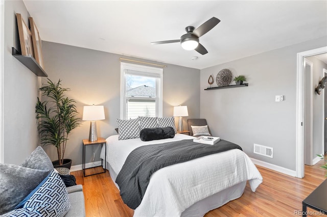 bedroom featuring light wood finished floors, a ceiling fan, visible vents, and baseboards