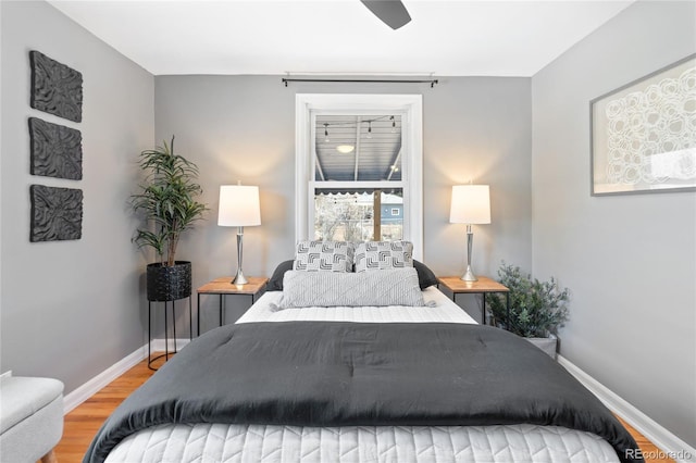 bedroom with a ceiling fan, baseboards, and wood finished floors