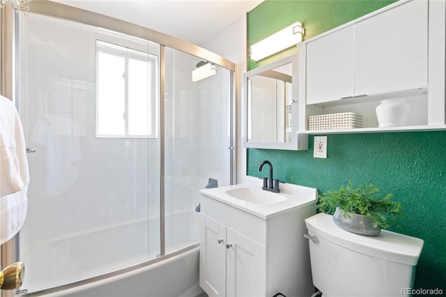 full bathroom with vanity, bath / shower combo with glass door, and a textured wall