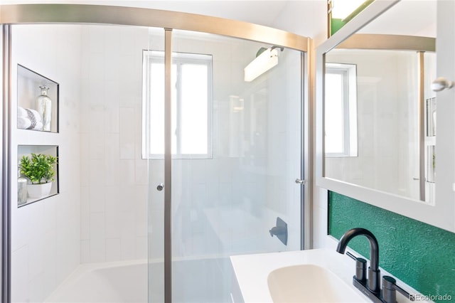 bathroom featuring a wealth of natural light, a shower with shower door, and a sink