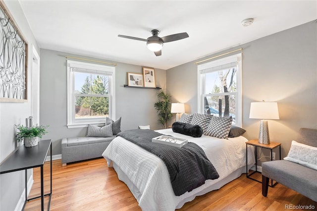 bedroom with ceiling fan, multiple windows, wood finished floors, and baseboards