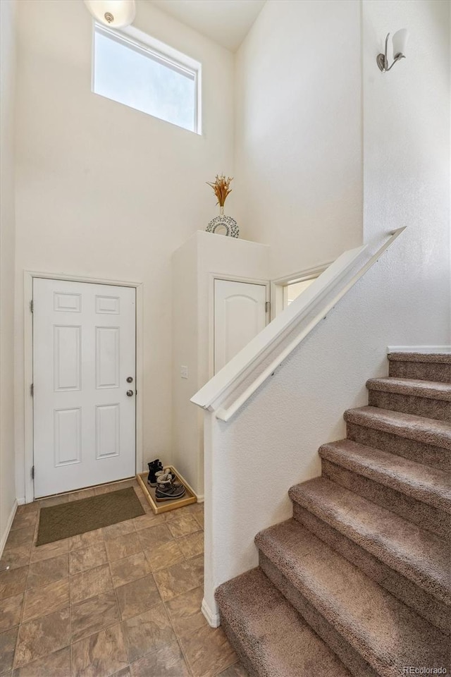 foyer entrance with stairs, stone finish flooring, and baseboards