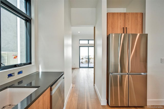 kitchen featuring a high ceiling, refrigerator, stainless steel refrigerator, and light hardwood / wood-style floors