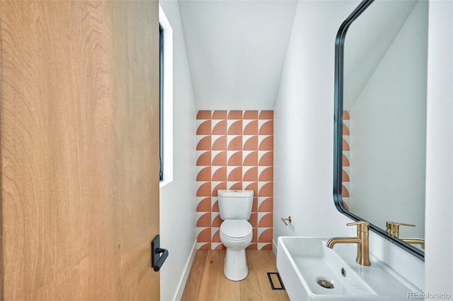 bathroom featuring lofted ceiling, sink, wood-type flooring, and toilet