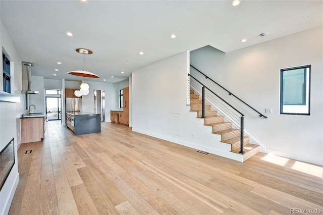 unfurnished living room with sink and light hardwood / wood-style floors