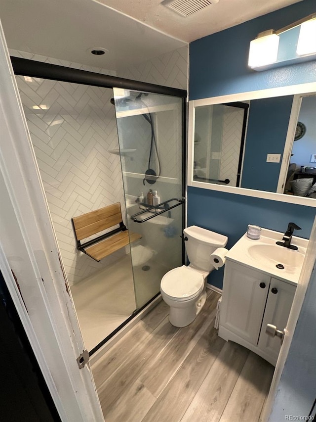 bathroom featuring hardwood / wood-style flooring, vanity, toilet, and walk in shower