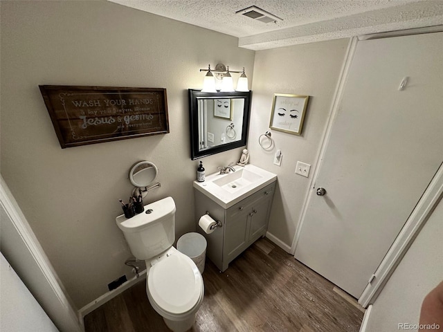 bathroom featuring vanity, wood-type flooring, a textured ceiling, and toilet