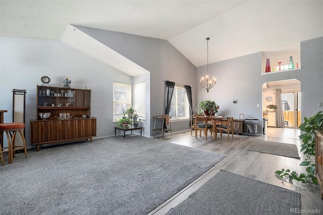 living area featuring high vaulted ceiling, wood finished floors, arched walkways, baseboards, and a chandelier