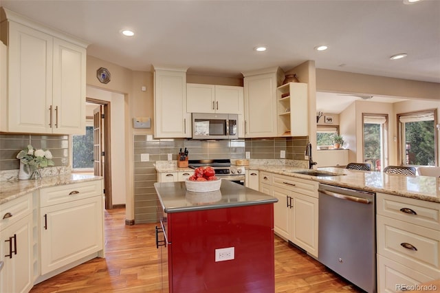 kitchen featuring decorative backsplash, light hardwood / wood-style floors, sink, and stainless steel appliances