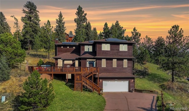 view of front of house with solar panels, a deck, a garage, and a lawn