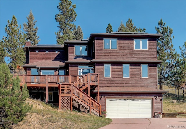 rear view of house with a wooden deck and a garage