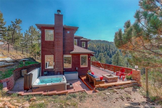 rear view of house featuring a fire pit, a deck, and a hot tub