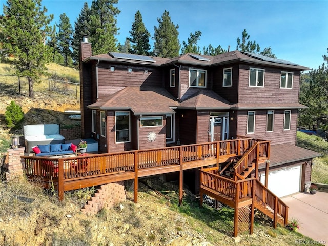 rear view of property featuring solar panels, a garage, and a deck