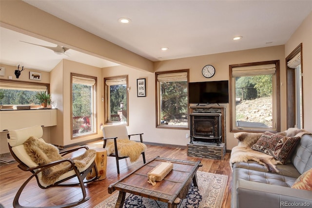 living room with hardwood / wood-style floors, a wood stove, and ceiling fan