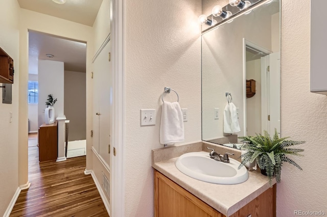 14700 E 104th Ave Unit 2802, Commerce City, CO 80022 - bathroom featuring wood finished floors, vanity, a textured wall, and baseboards