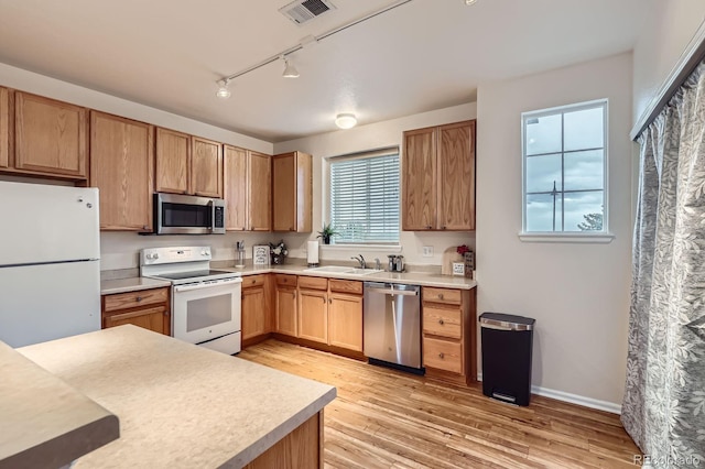 14700 E 104th Ave Unit 2802, Commerce City, CO 80022 - kitchen with appliances with stainless steel finishes, a sink, track lighting, light wood-style flooring, and light countertops