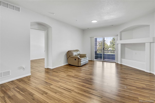 5255 Memphis St Unit 317, Denver, CO 80239 - unfurnished room with arched walkways, wood finished floors, and a textured ceiling