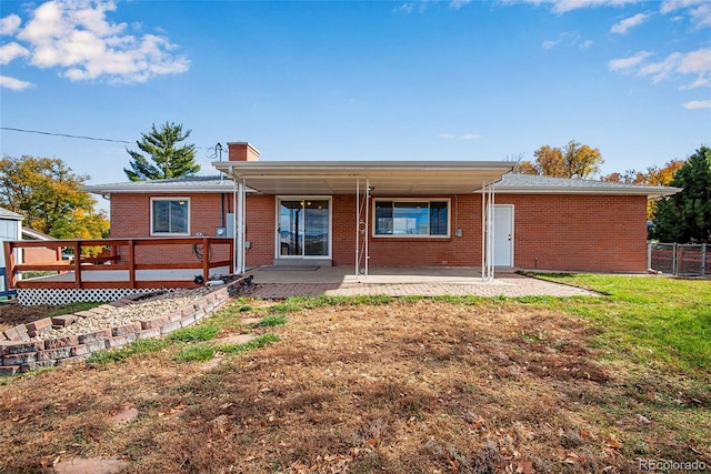 back of house with a patio area, brick siding, a yard, and a chimney